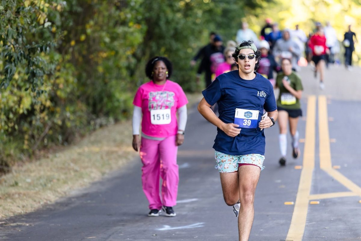 A runner in a navy HRH shirt in a crowd of runners on the course.